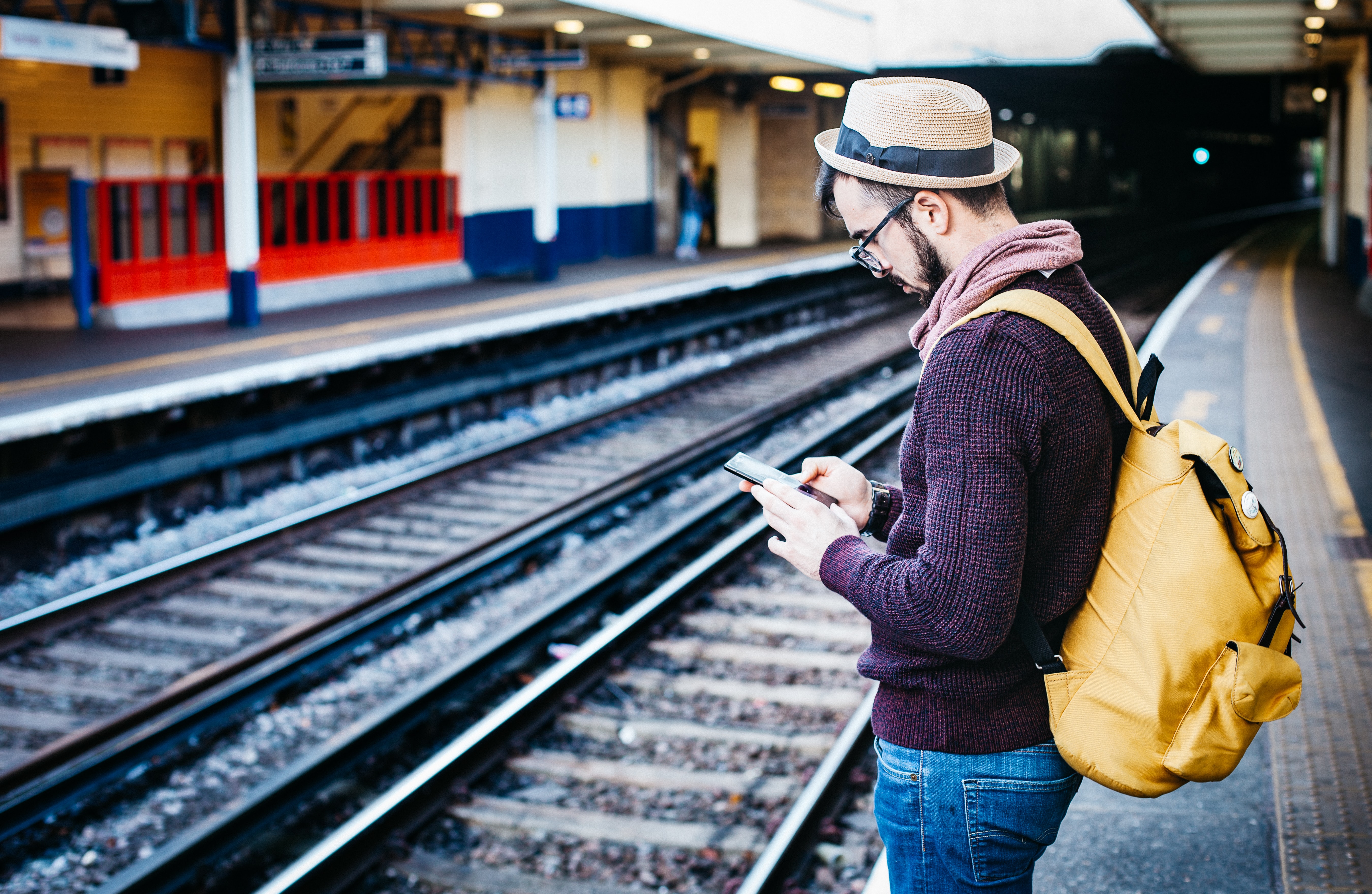 Person standing in a station, looking at his phone